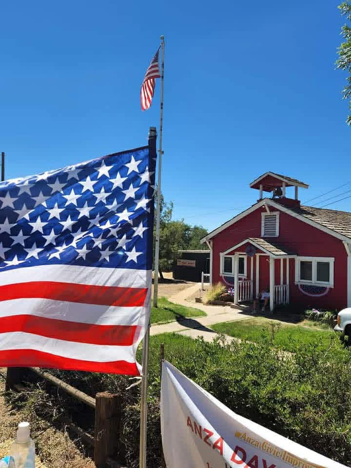 The Little Red Schoolhouse with Anza Days banner and flags