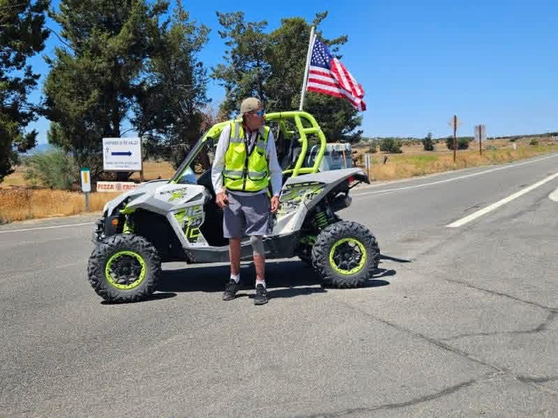 Parade marshal in a high-visibility vest with side-by-side and American flag