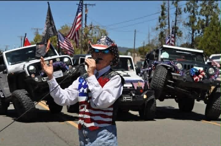 Woman in patriotic vest waving at the parade